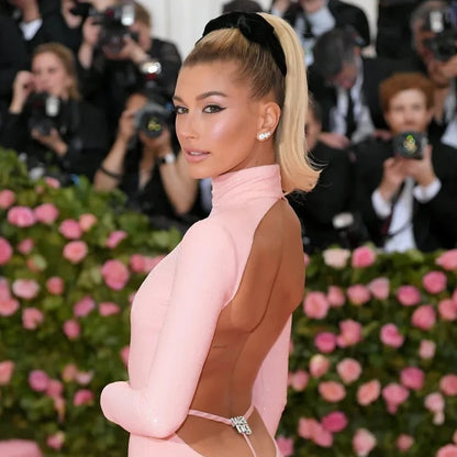 Hailey Bieber sul red carpet con vestito rosa e orecchini punto luce