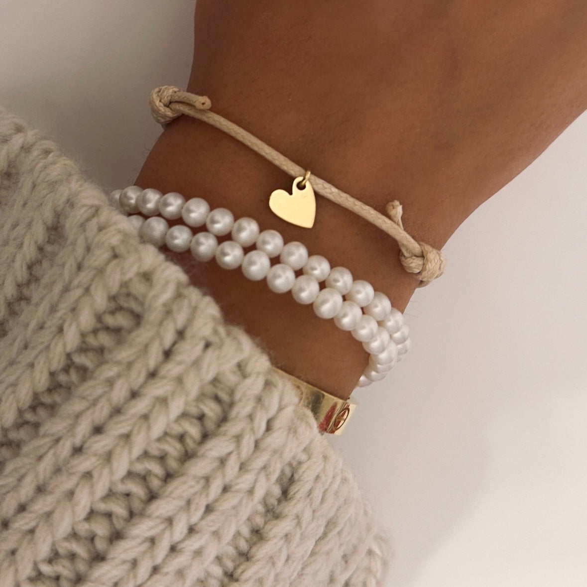 bracciale autunnale con cordino beige e ciondolo a forma di cuore abbinato a bracciale perline bianche