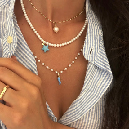 foto pendente corno portafortuna azzurro indossato con collana di perle